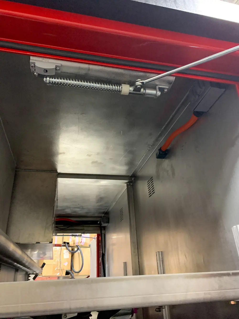 Exterior view of small fire truck showing cab, body compartments, and wheel/tire area.