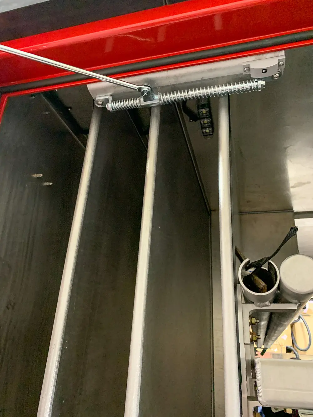 Exterior view of small fire truck showing cab, body compartments, and wheel/tire area.