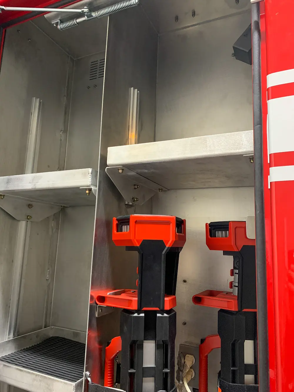 Exterior view of small fire truck showing cab, body compartments, and wheel/tire area.