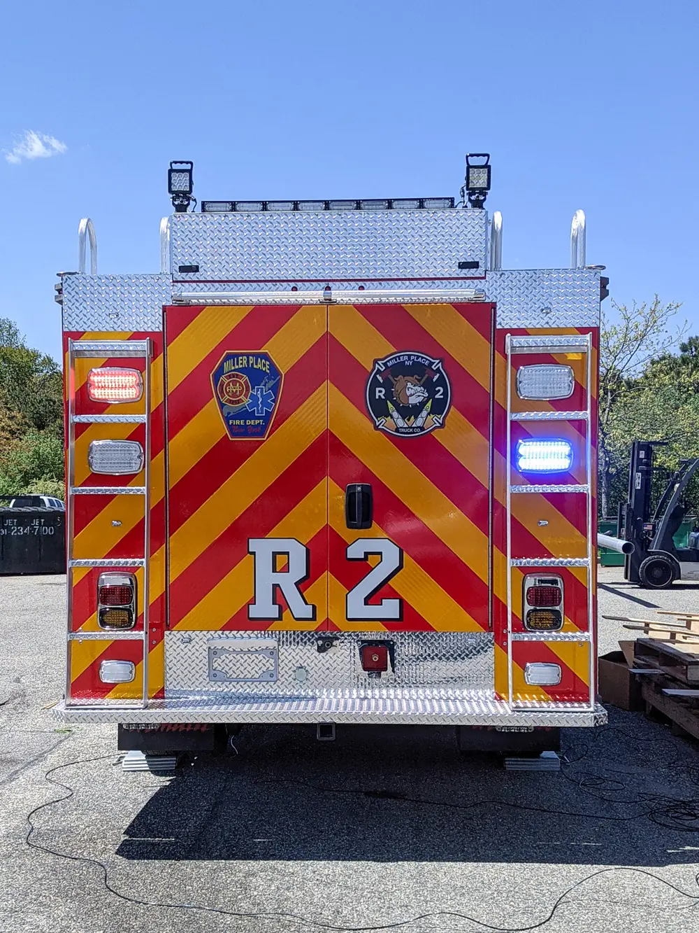 Exterior view of small fire truck showing cab, body compartments, and wheel/tire area.