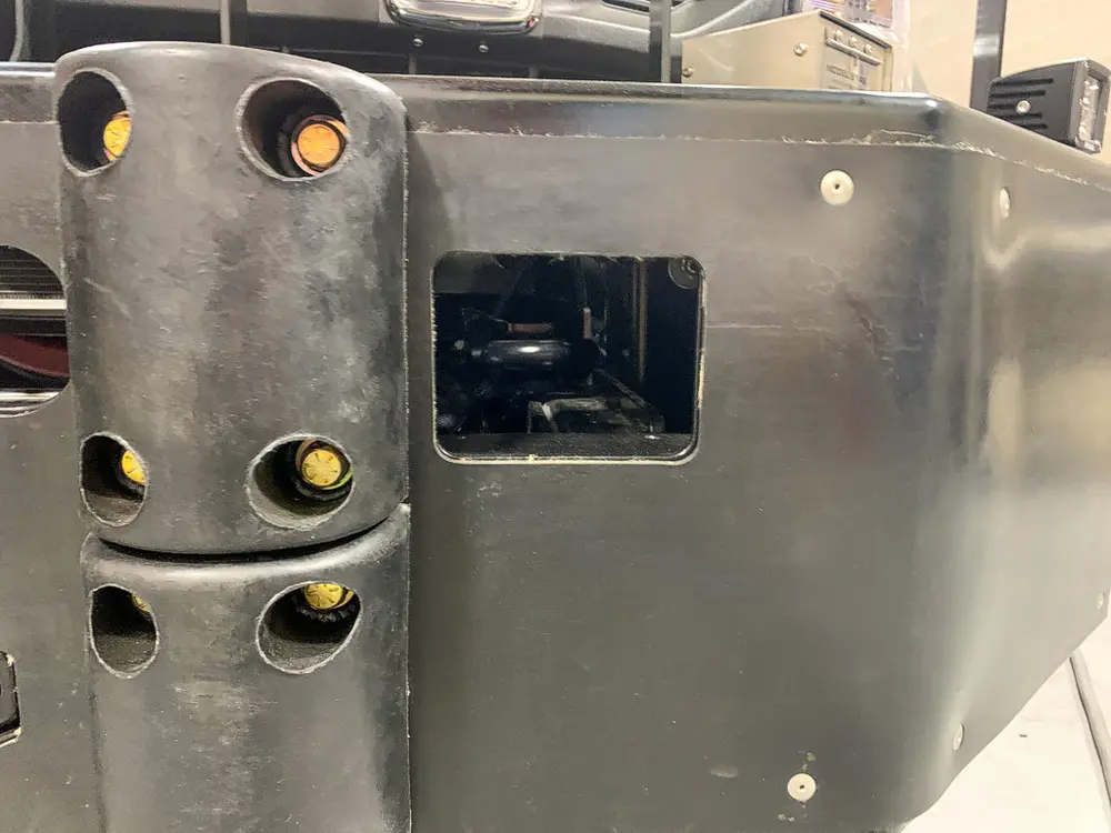 Exterior view of small fire truck showing cab, body compartments, and wheel/tire area.