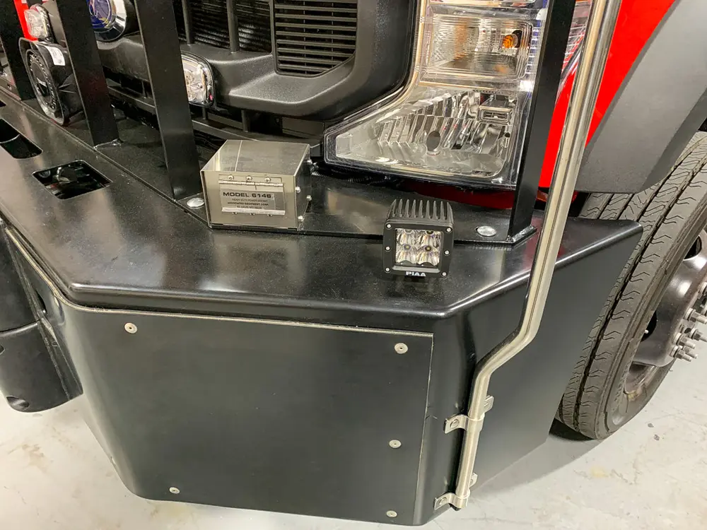 Exterior view of small fire truck showing cab, body compartments, and wheel/tire area.