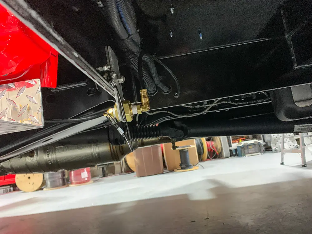 Exterior view of small fire truck showing cab, body compartments, and wheel/tire area.