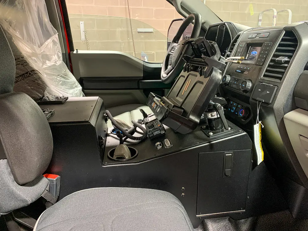 Exterior view of small fire truck showing cab, body compartments, and wheel/tire area.