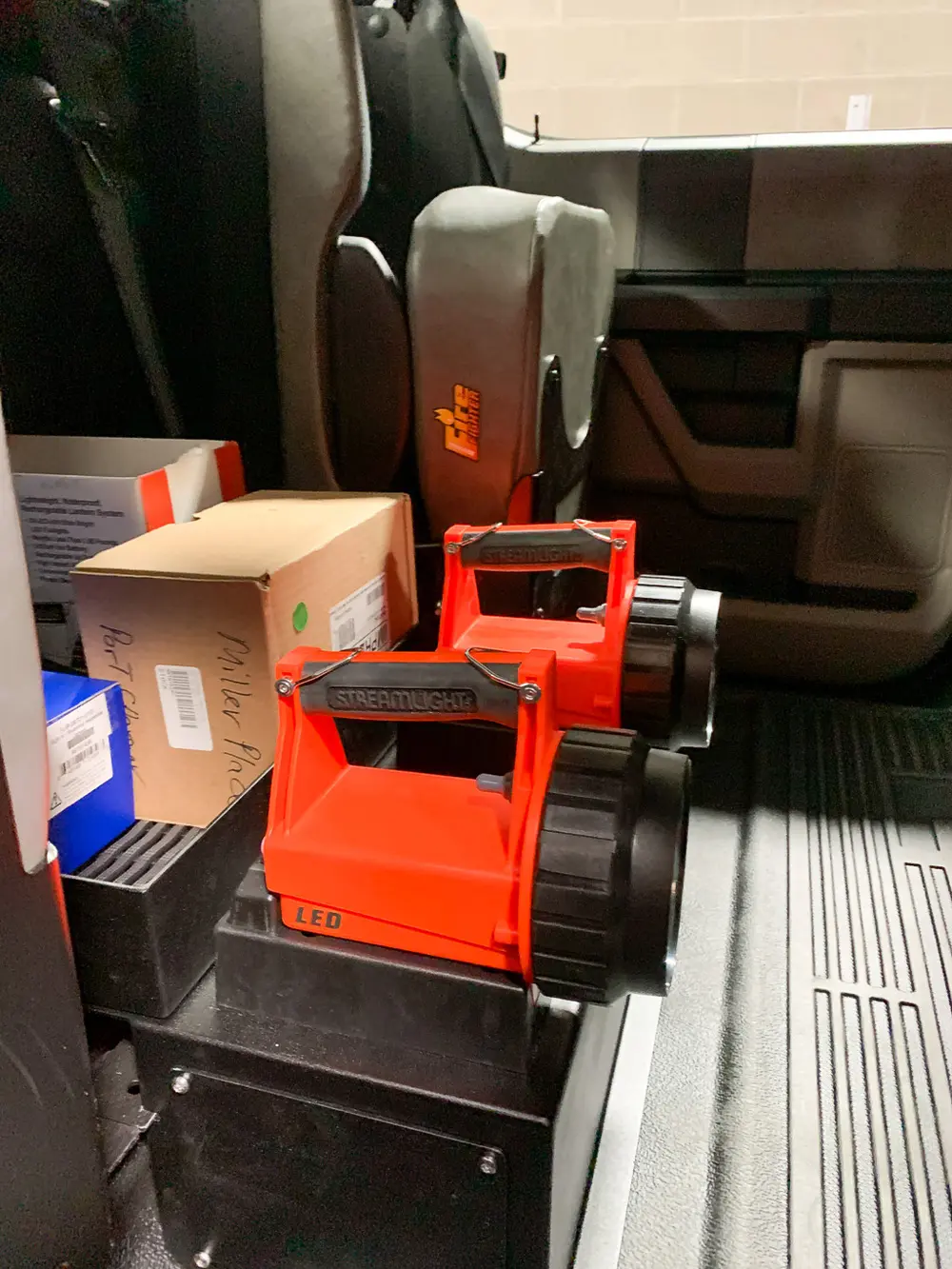 Exterior view of small fire truck showing cab, body compartments, and wheel/tire area.