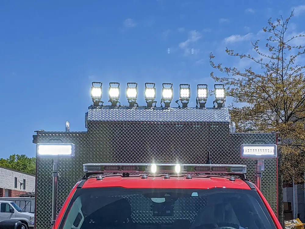 Exterior view of small fire truck showing cab, body compartments, and wheel/tire area.
