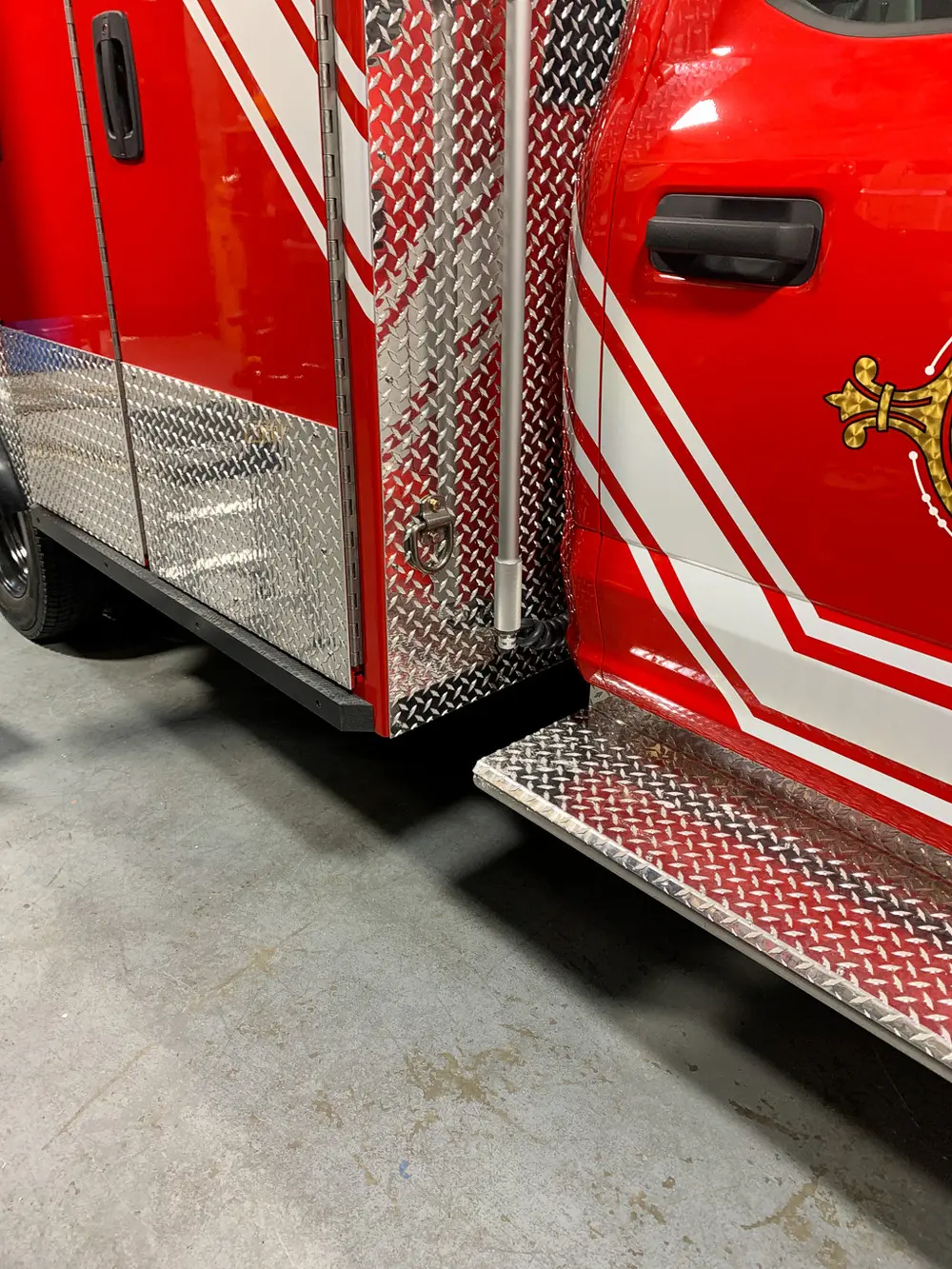 Exterior view of small fire truck showing cab, body compartments, and wheel/tire area.