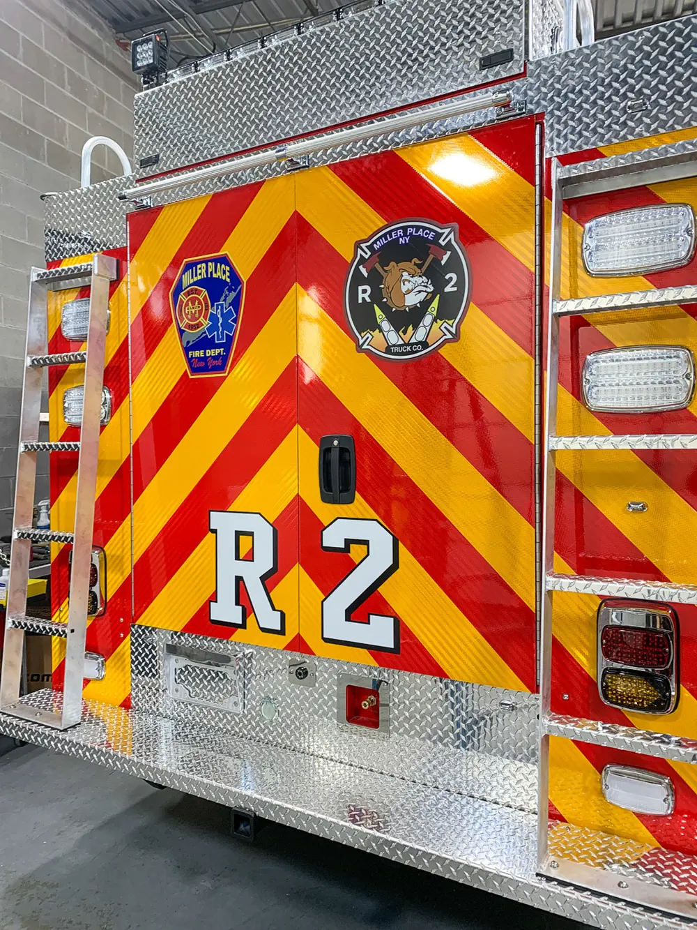 Exterior view of small fire truck showing cab, body compartments, and wheel/tire area.