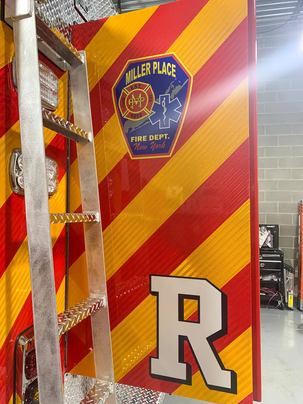 Exterior view of small fire truck showing cab, body compartments, and wheel/tire area.