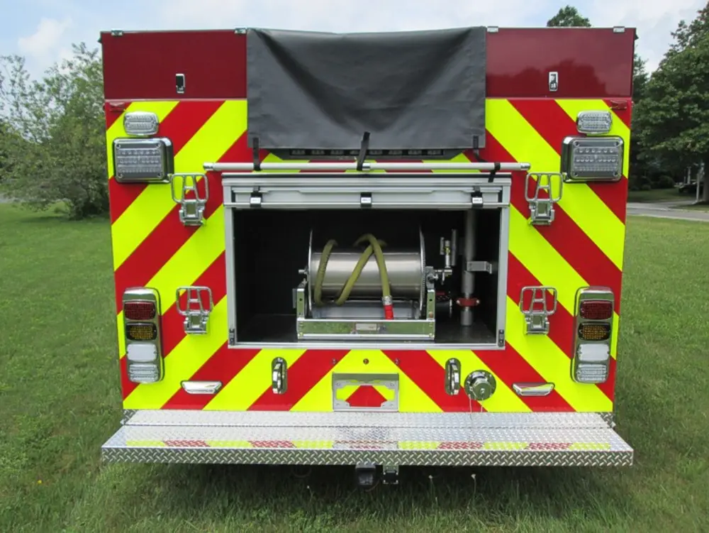 Exterior view of small fire truck showing cab, body compartments, and wheel/tire area.