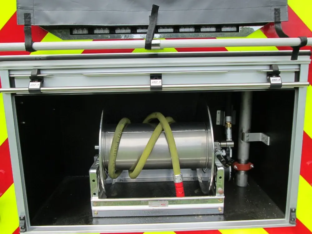 Exterior view of small fire truck showing cab, body compartments, and wheel/tire area.