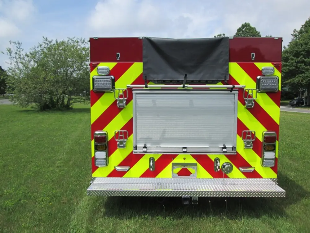 Exterior view of small fire truck showing cab, body compartments, and wheel/tire area.