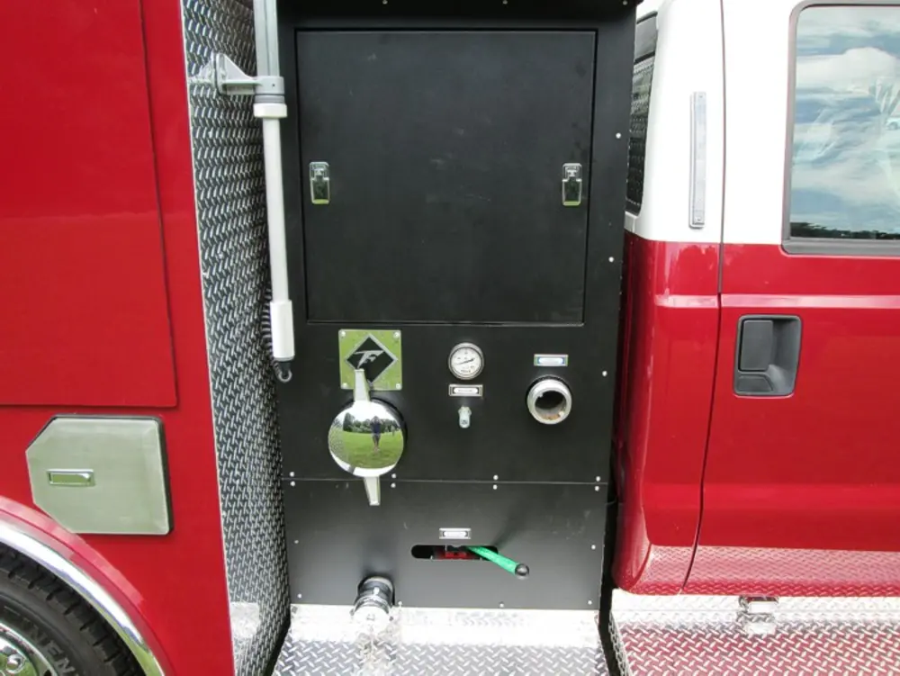 Exterior view of small fire truck showing cab, body compartments, and wheel/tire area.