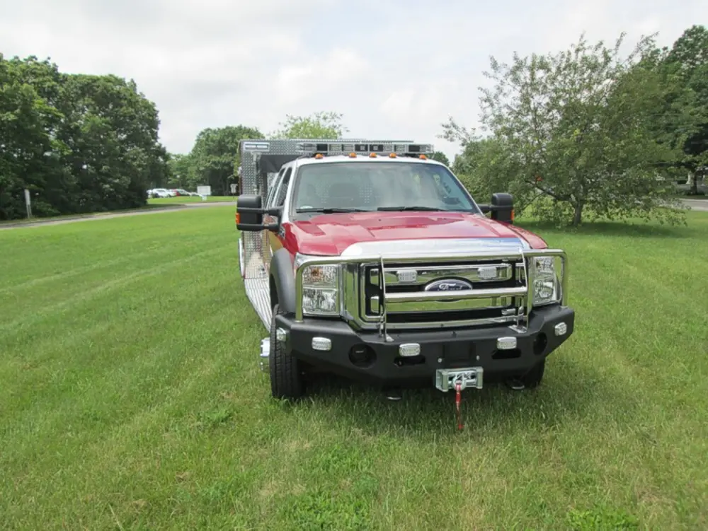 Exterior view of small fire truck showing cab, body compartments, and wheel/tire area.