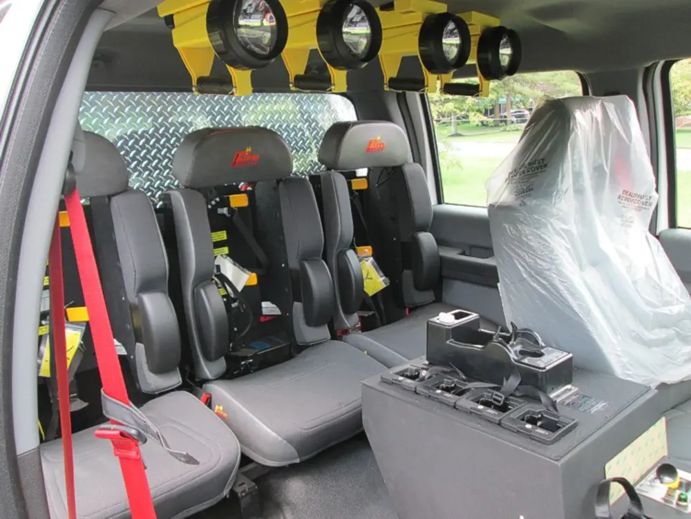 Exterior view of small fire truck showing cab, body compartments, and wheel/tire area.