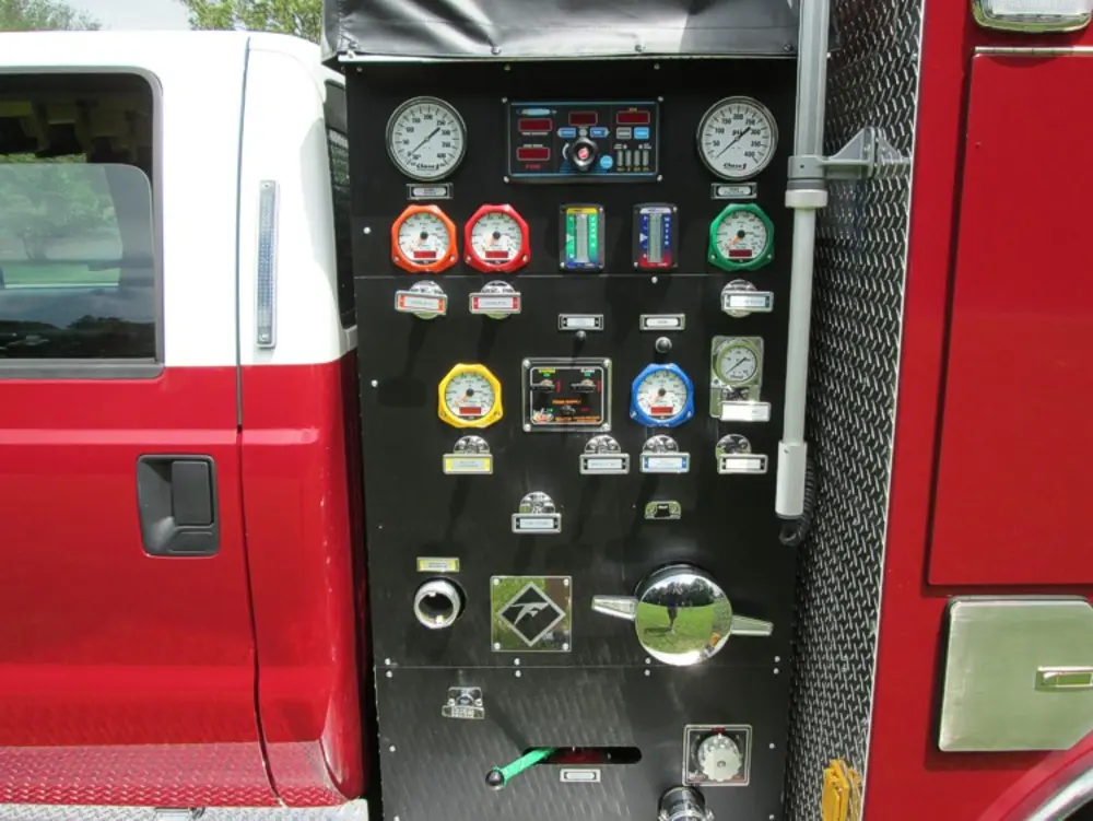Exterior view of small fire truck showing cab, body compartments, and wheel/tire area.