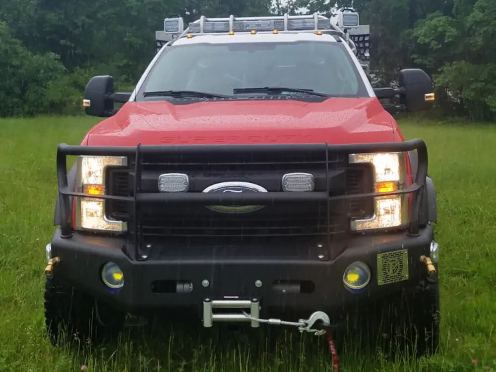 Exterior view of small fire truck showing cab, body compartments, and wheel/tire area.