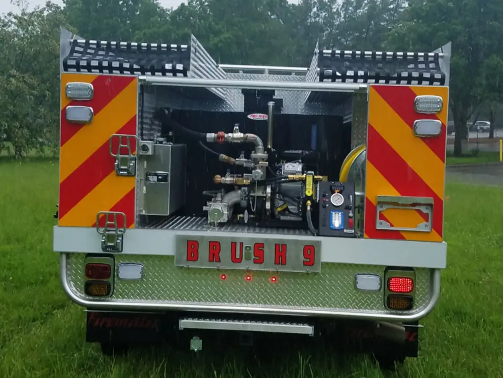 Exterior view of small fire truck showing cab, body compartments, and wheel/tire area.