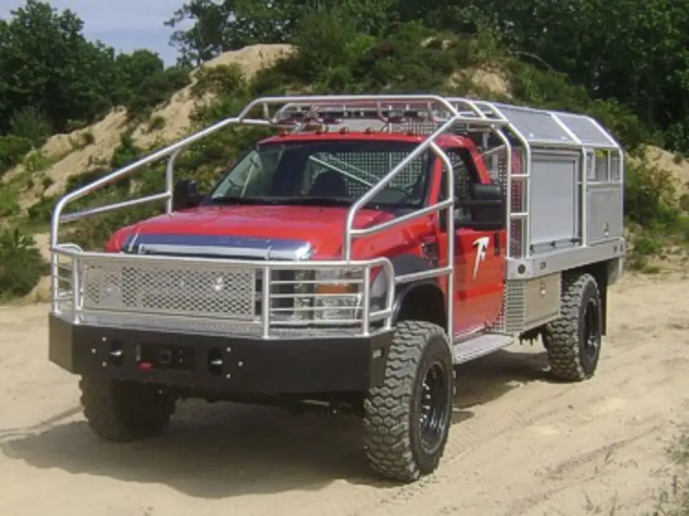 Exterior view of small fire truck showing cab, body compartments, and wheel/tire area.