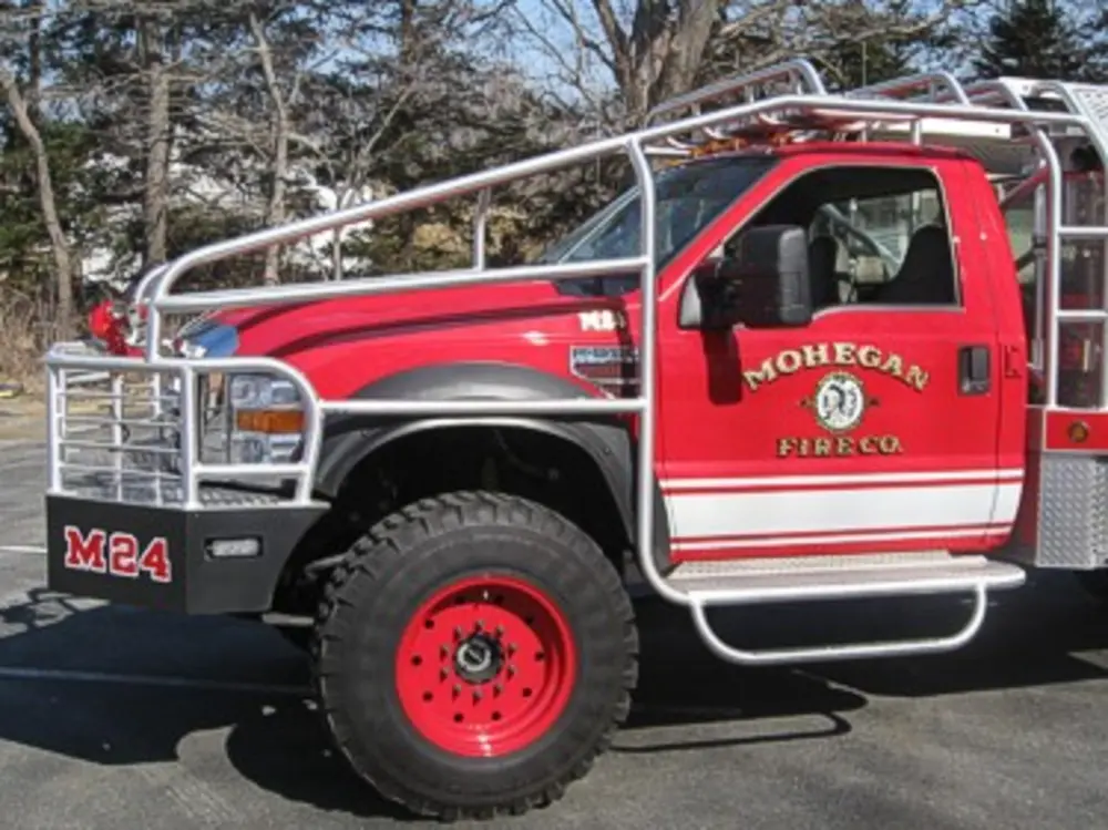 Exterior view of small fire truck showing cab, body compartments, and wheel/tire area.