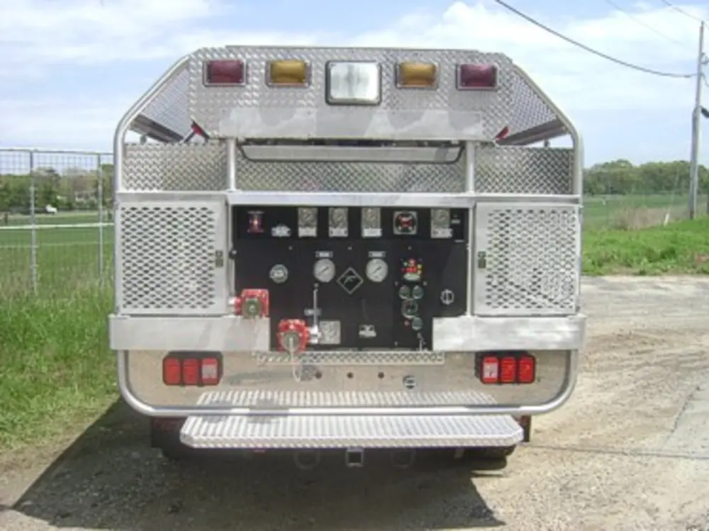 Exterior view of small fire truck showing cab, body compartments, and wheel/tire area.