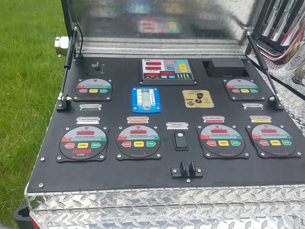 Exterior view of small fire truck showing cab, body compartments, and wheel/tire area.