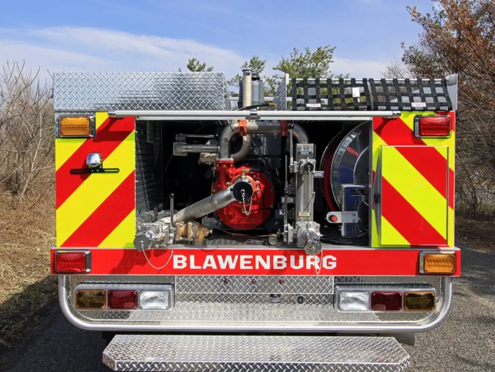Exterior view of small fire truck showing cab, body compartments, and wheel/tire area.