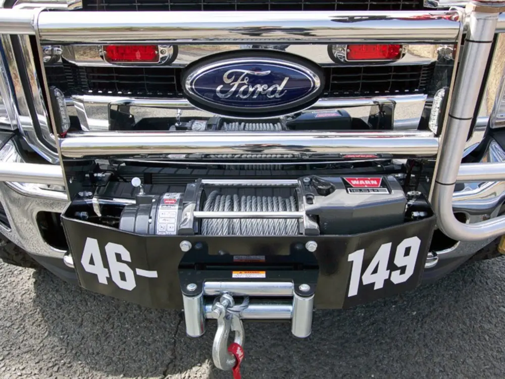 Exterior view of small fire truck showing cab, body compartments, and wheel/tire area.
