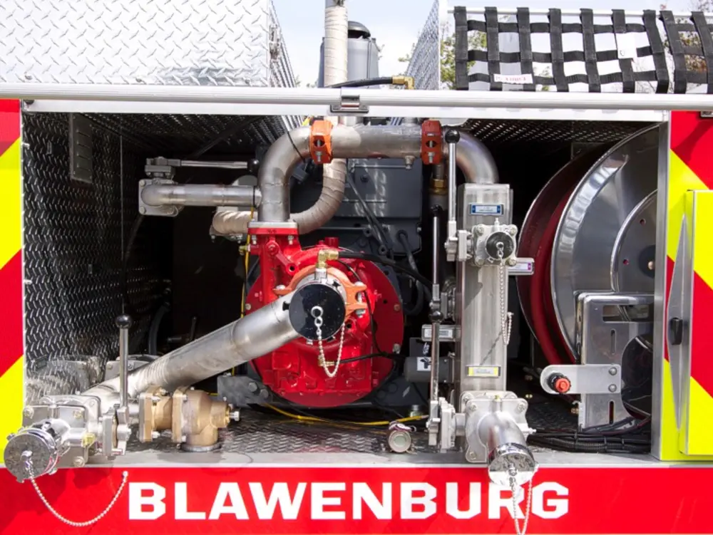 Exterior view of small fire truck showing cab, body compartments, and wheel/tire area.