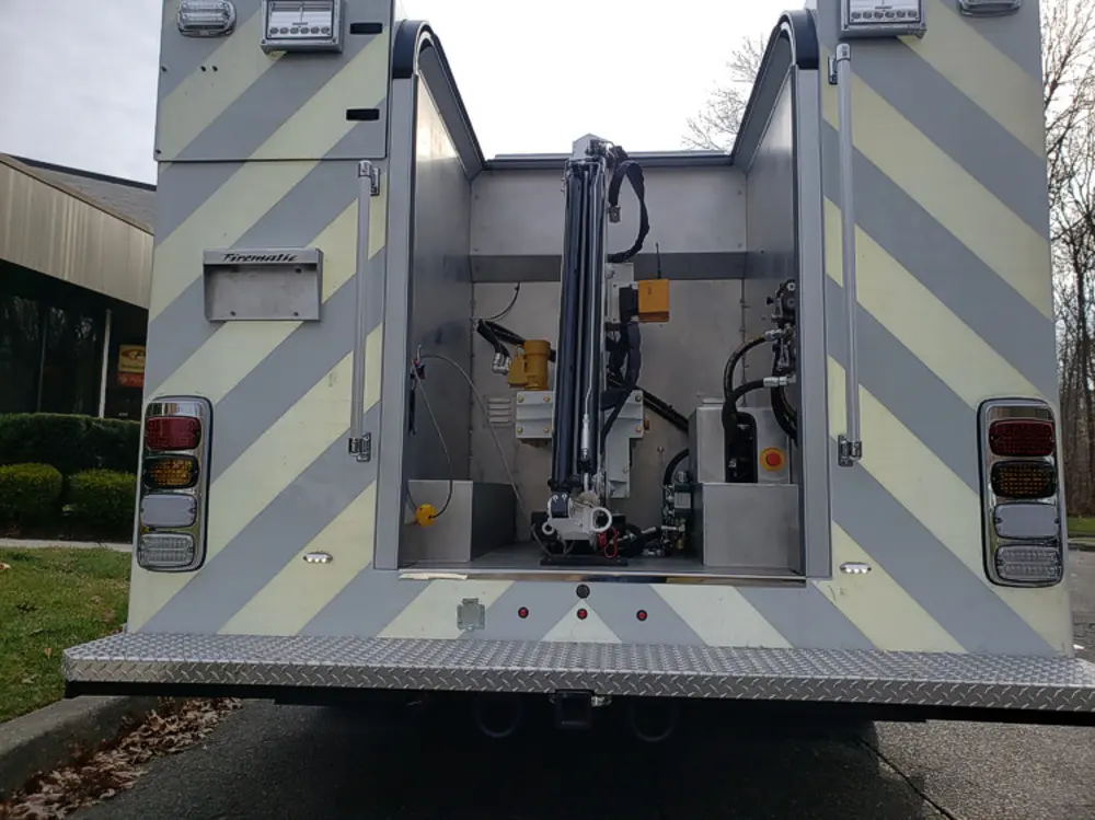 Exterior view of small fire truck showing cab, body compartments, and wheel/tire area.