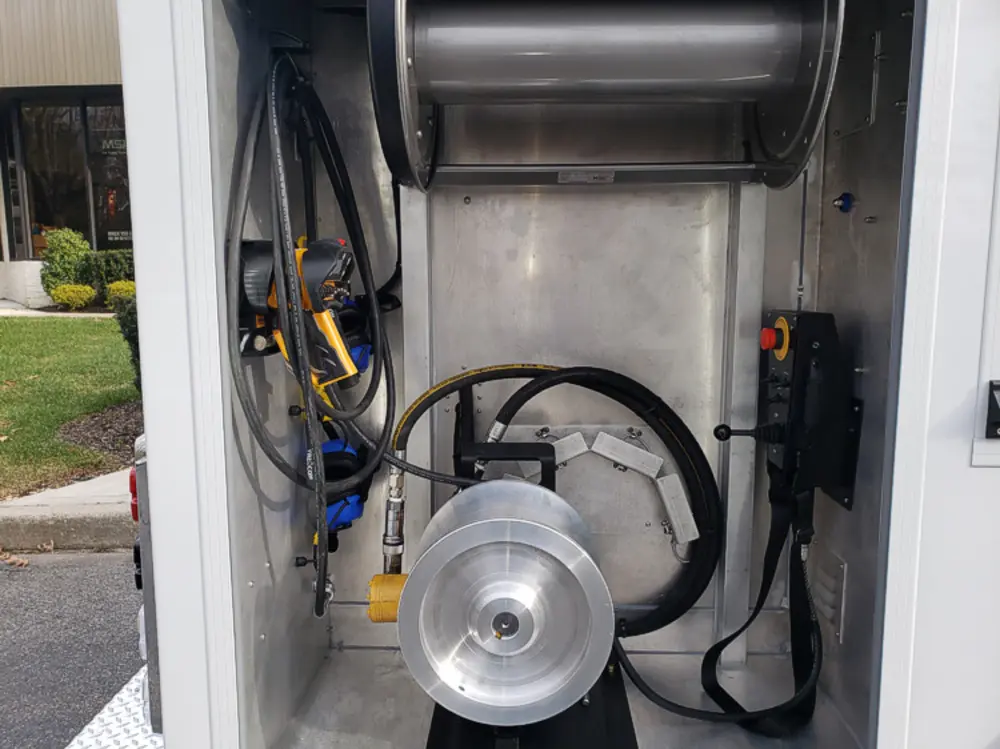 Exterior view of small fire truck showing cab, body compartments, and wheel/tire area.