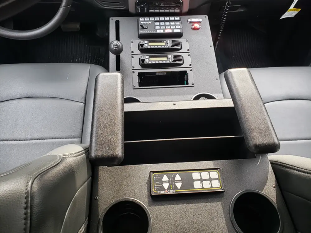 Exterior view of small fire truck showing cab, body compartments, and wheel/tire area.