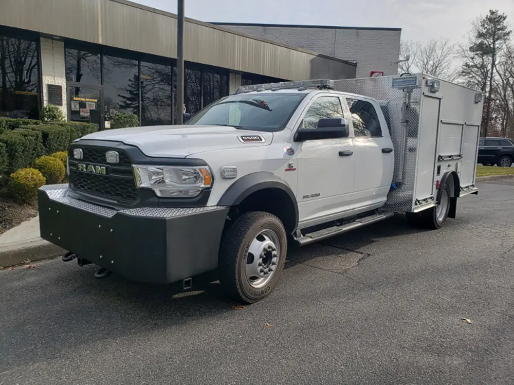 Exterior view of small fire truck showing cab, body compartments, and wheel/tire area.