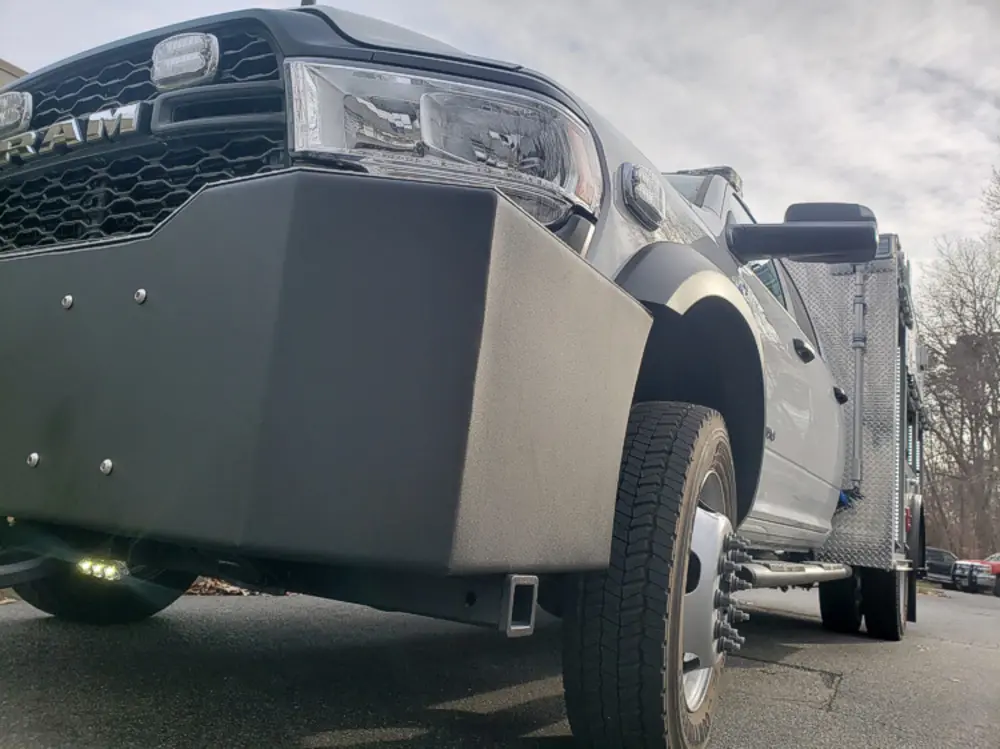Exterior view of small fire truck showing cab, body compartments, and wheel/tire area.