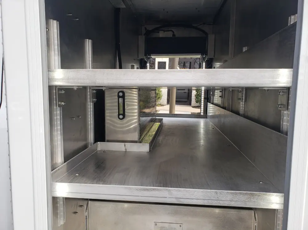 Exterior view of small fire truck showing cab, body compartments, and wheel/tire area.