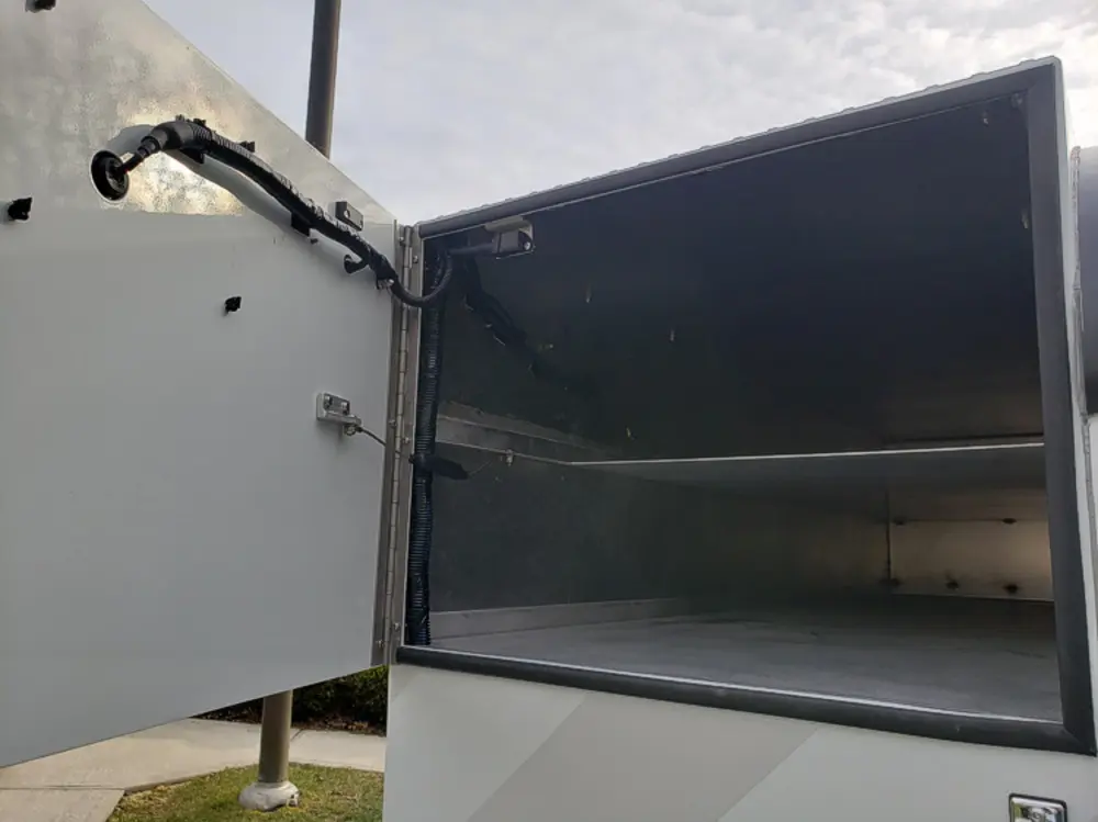 Exterior view of small fire truck showing cab, body compartments, and wheel/tire area.