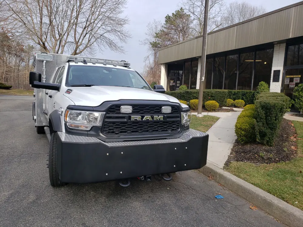 Exterior view of small fire truck showing cab, body compartments, and wheel/tire area.