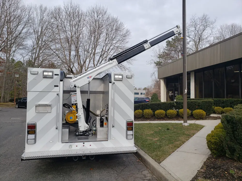 Exterior view of small fire truck showing cab, body compartments, and wheel/tire area.