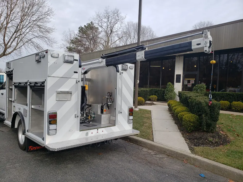 Exterior view of small fire truck showing cab, body compartments, and wheel/tire area.