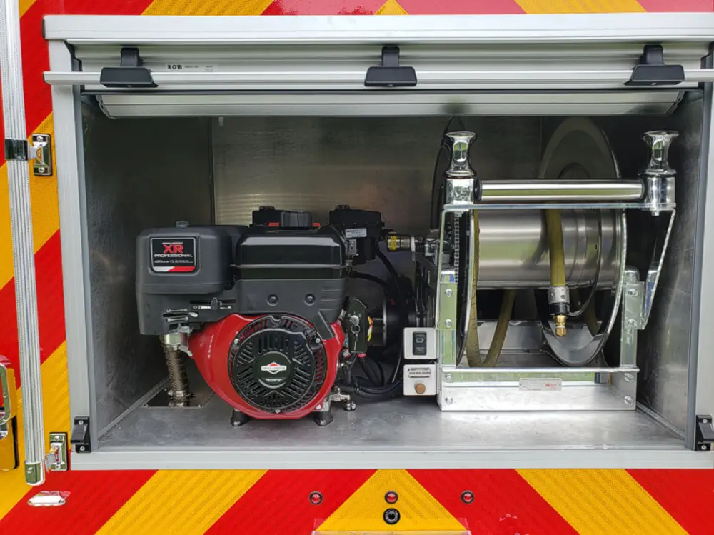 Exterior view of small fire truck showing cab, body compartments, and wheel/tire area.