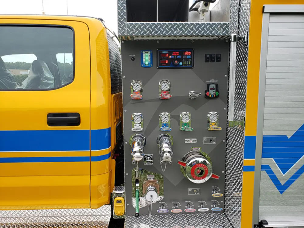 Exterior view of small fire truck showing cab, body compartments, and wheel/tire area.