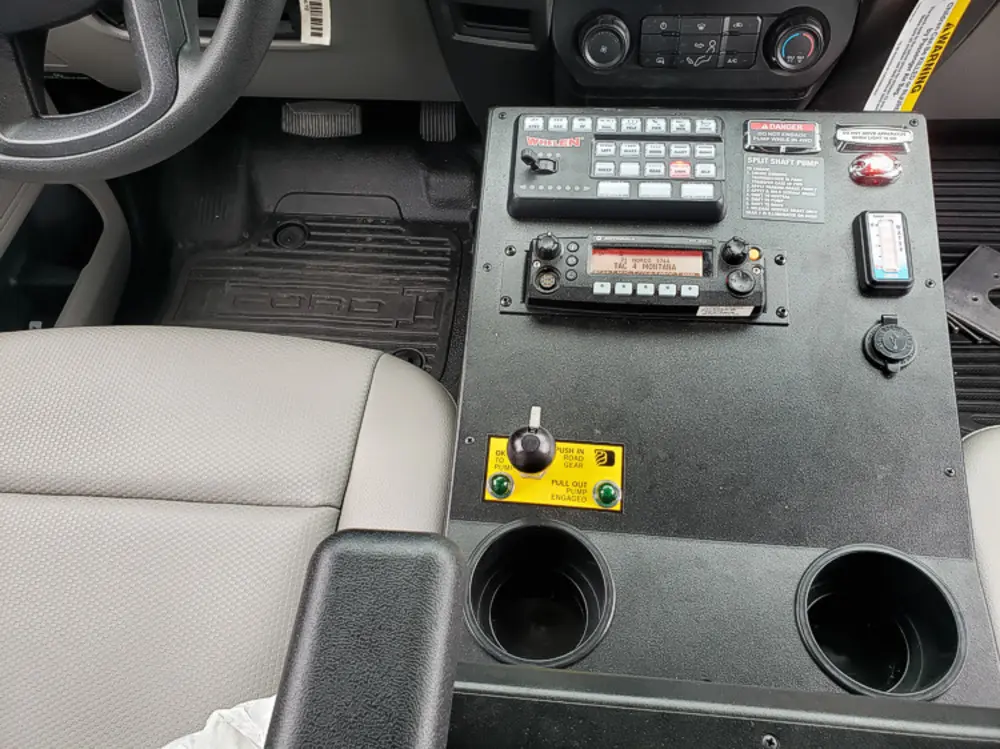 Exterior view of small fire truck showing cab, body compartments, and wheel/tire area.