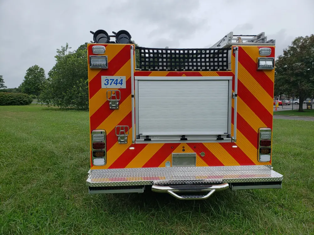Exterior view of small fire truck showing cab, body compartments, and wheel/tire area.