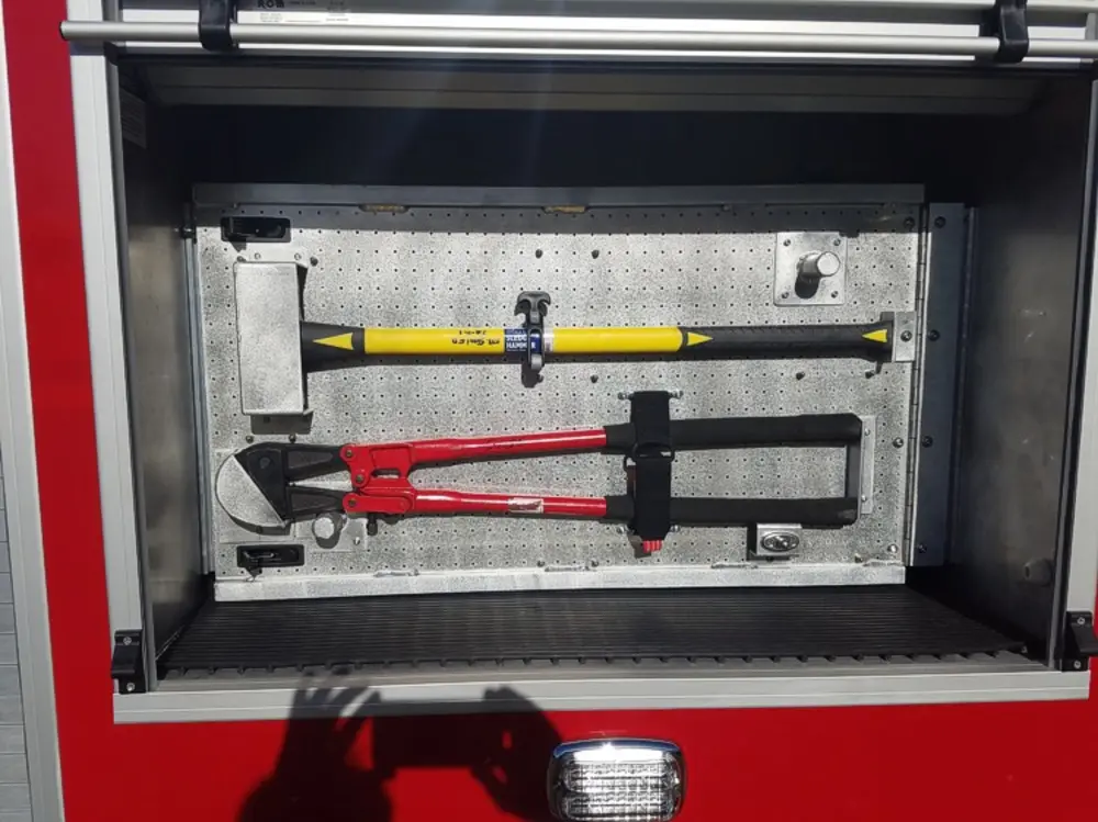 Exterior view of small fire truck showing cab, body compartments, and wheel/tire area.