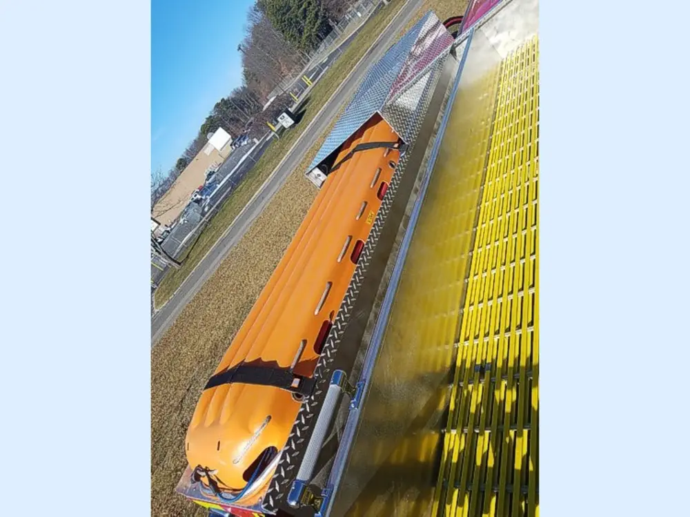 Exterior view of small fire truck showing cab, body compartments, and wheel/tire area.