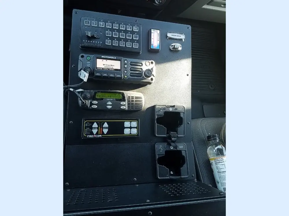 Exterior view of small fire truck showing cab, body compartments, and wheel/tire area.