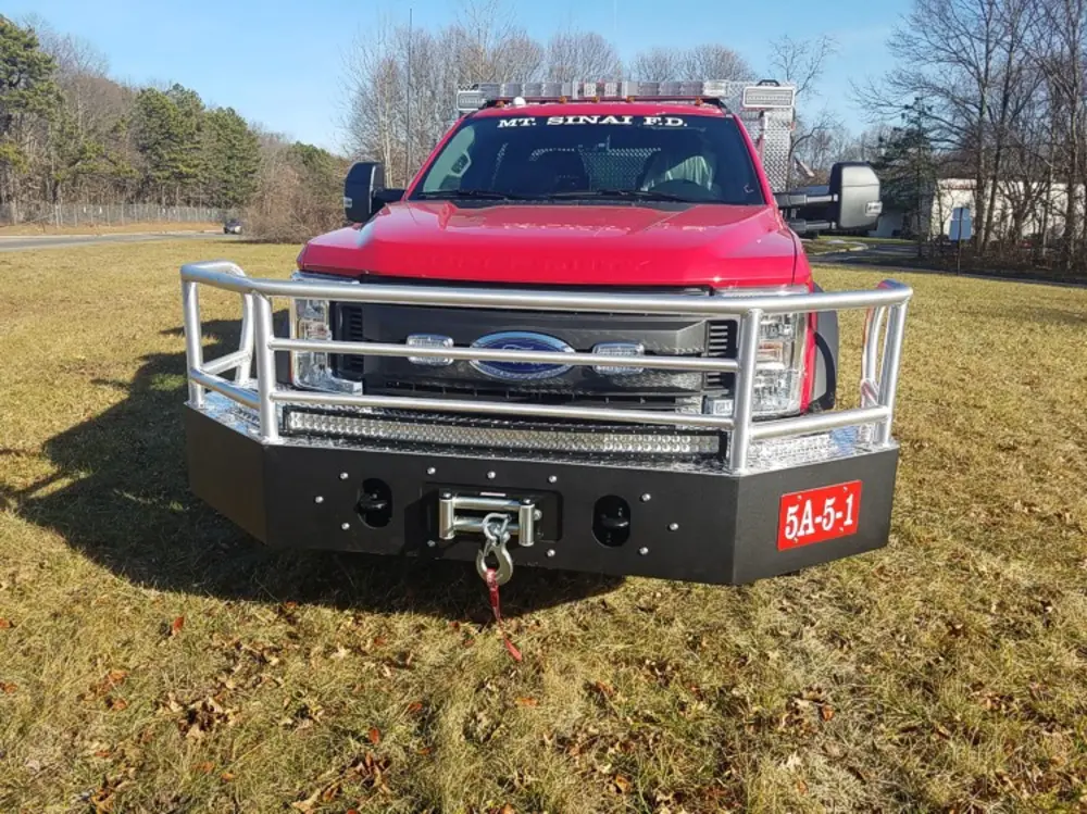 Exterior view of small fire truck showing cab, body compartments, and wheel/tire area.