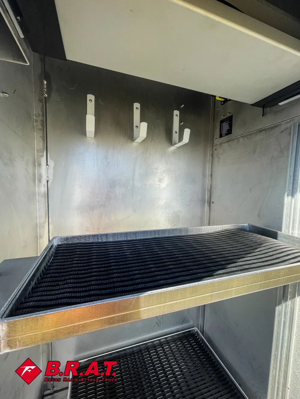 Compartment interior close-up with hooks and ribbed floor tray.