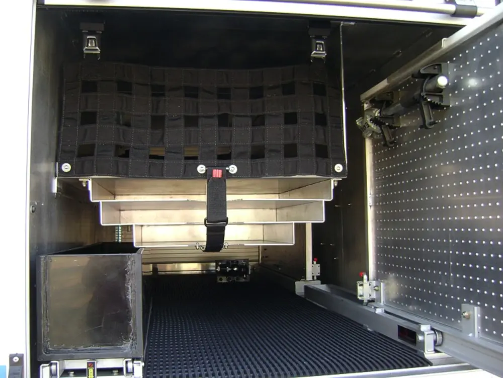 Exterior view of small fire truck showing cab, body compartments, and wheel/tire area.