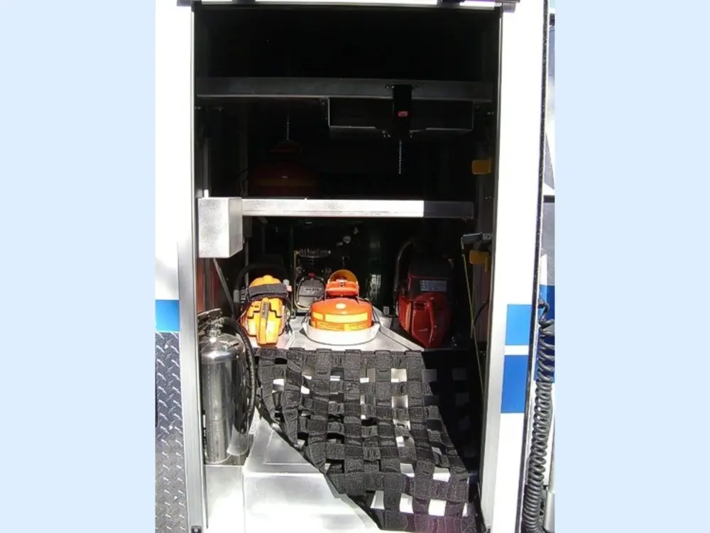 Exterior view of small fire truck showing cab, body compartments, and wheel/tire area.